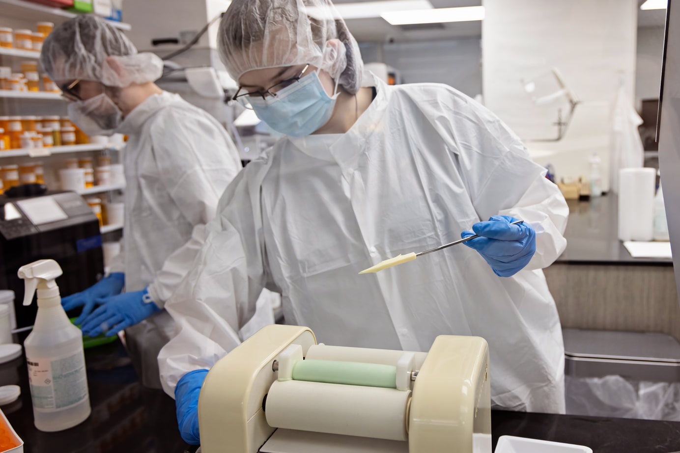 Two scientists in a laboratory setting, one preparing a syringe with a needle.